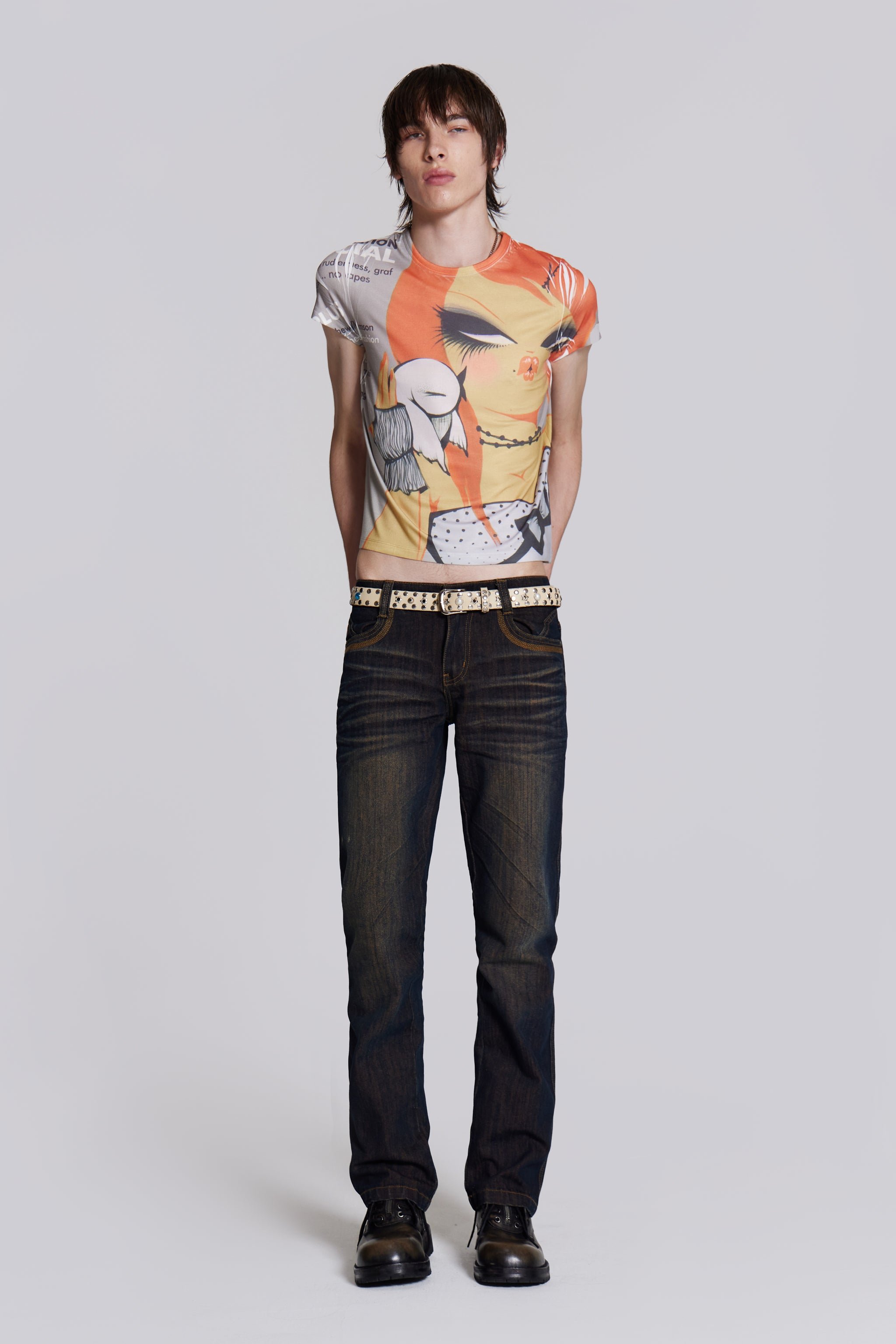Male wearing graphic print t-shirt styled with denim jeans, studded belt and leather boots.