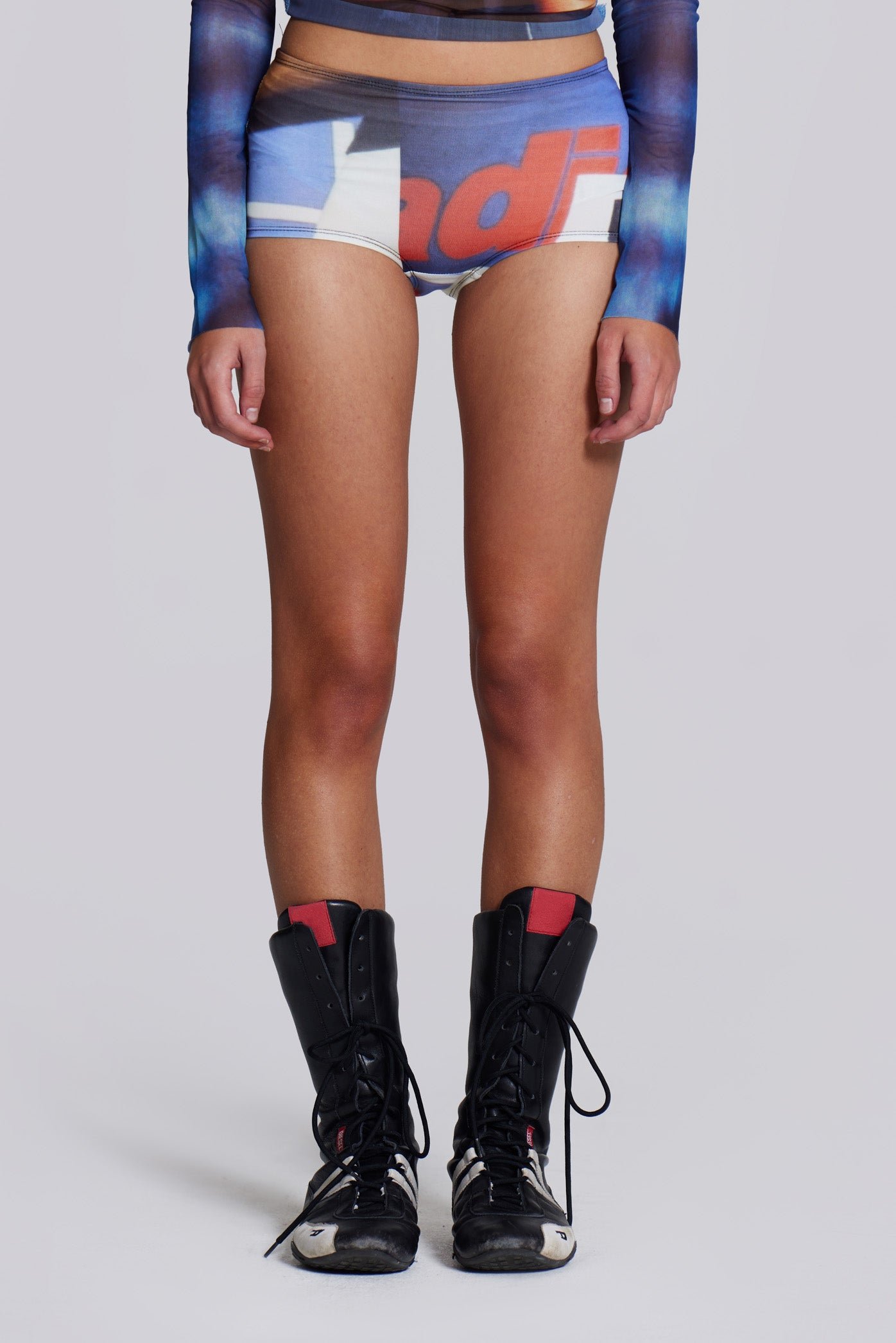 Woman wearing Jaded London and Sleazenation graphic printed hot pants, styled with black boots.