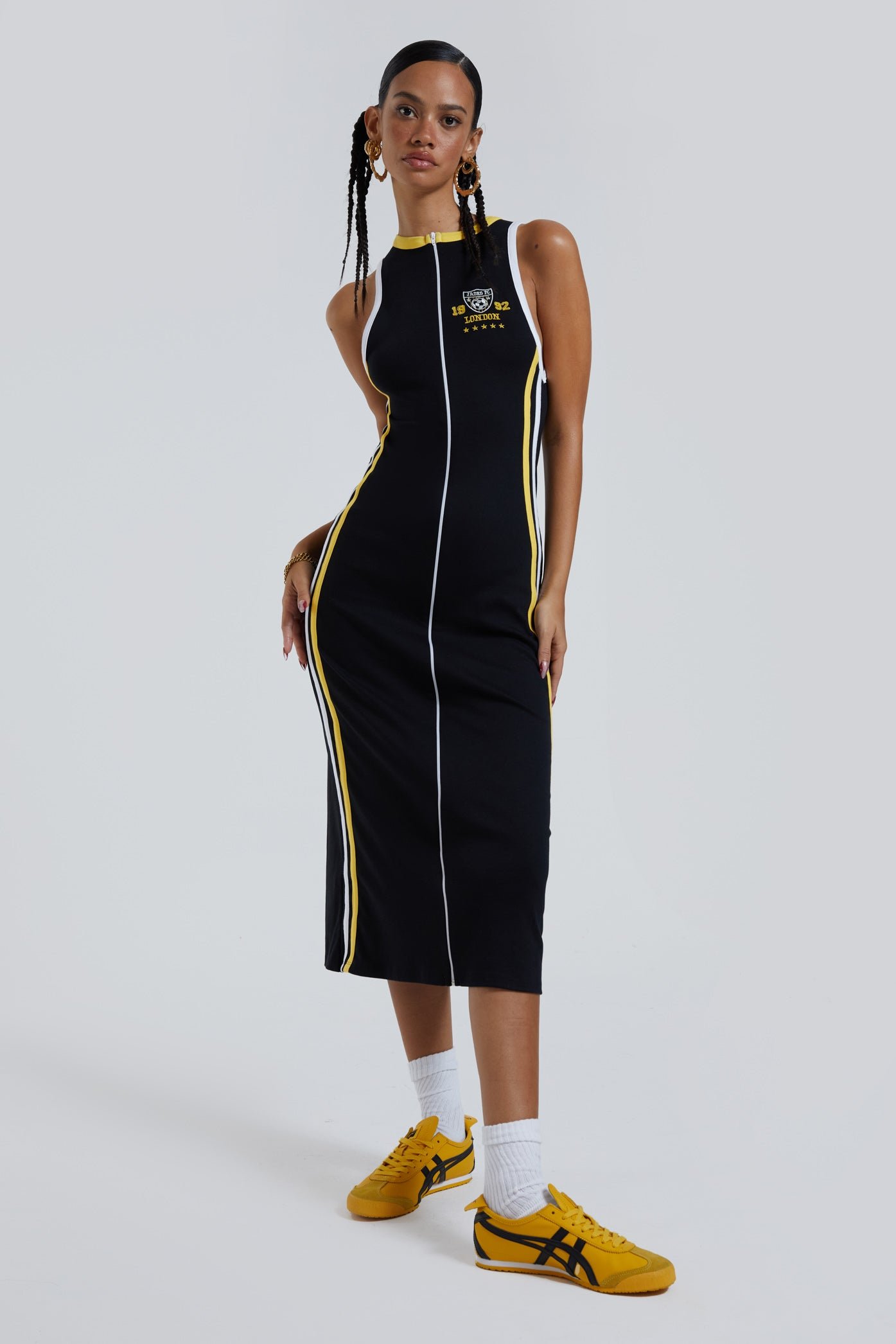  Female wearing black sporty style zip up front maxi length dress with side stripe detail. 
